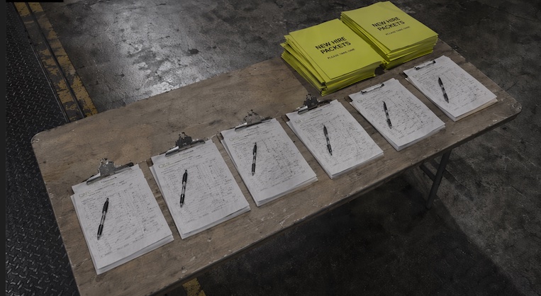 Public sample myCrewIQ crew sign-in sheets staged on clipboards at a job site